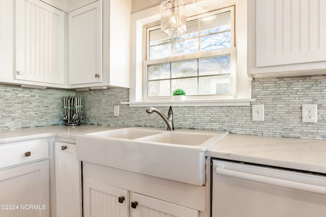 kitchen featuring light stone counters, sink, white cabinetry, decorative backsplash, and white dishwasher