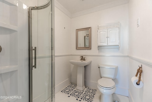 bathroom with tile patterned flooring, crown molding, a shower with shower door, and toilet