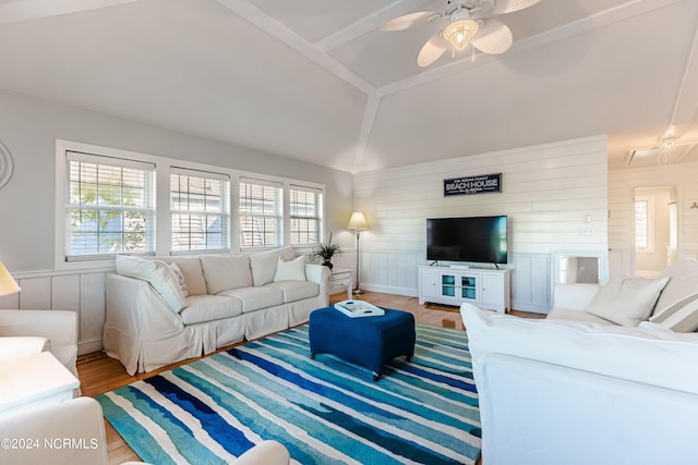 living room with light hardwood / wood-style flooring, wooden walls, vaulted ceiling, and ceiling fan