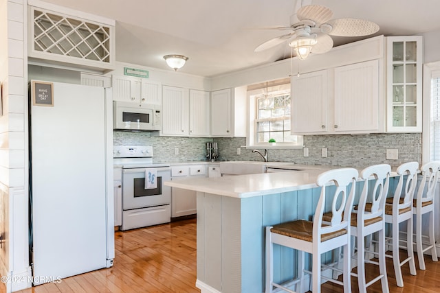 kitchen featuring light hardwood / wood-style floors, white cabinets, kitchen peninsula, white appliances, and ceiling fan