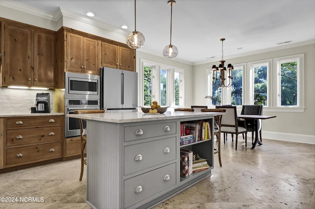 kitchen with gray cabinets, appliances with stainless steel finishes, a center island, light stone counters, and decorative light fixtures