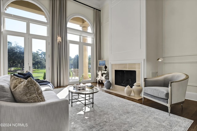 living room featuring a tiled fireplace, a towering ceiling, and dark hardwood / wood-style flooring