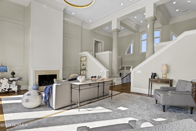 living room with dark wood-type flooring, ornamental molding, a fireplace, and decorative columns