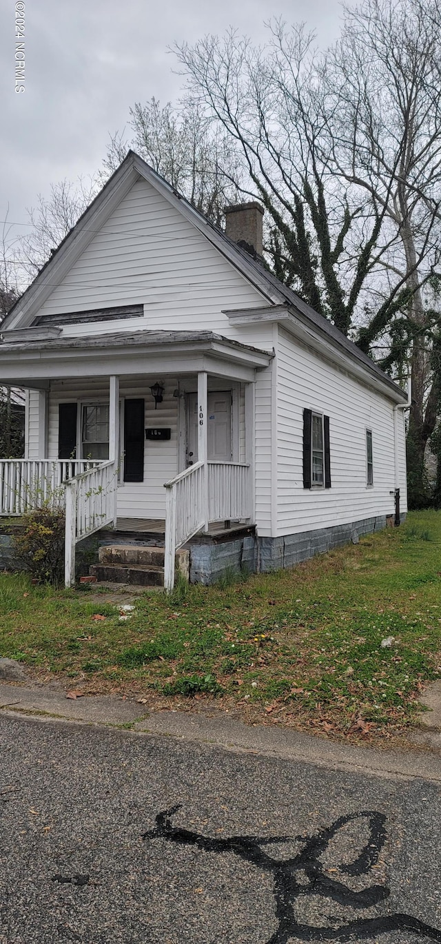 view of front facade featuring covered porch and a chimney