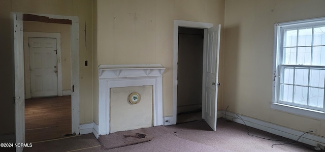 unfurnished bedroom with a baseboard radiator, multiple windows, and carpet