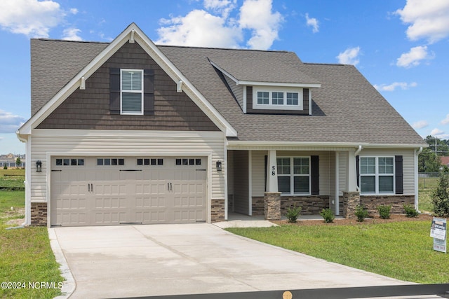 craftsman inspired home with a front yard, covered porch, and a garage