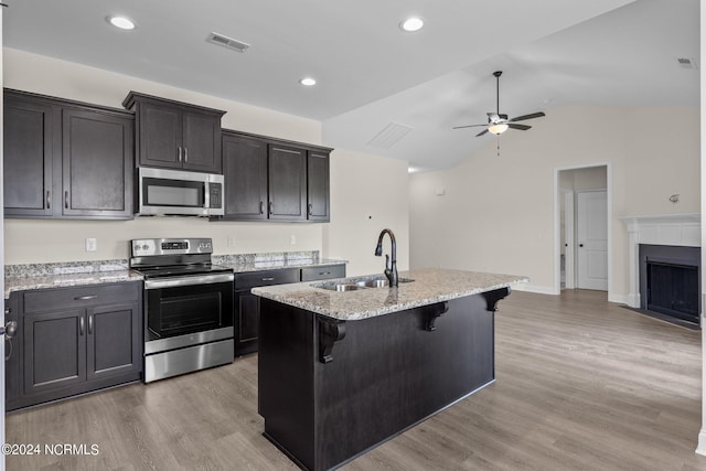 kitchen featuring sink, a kitchen breakfast bar, stainless steel appliances, and an island with sink