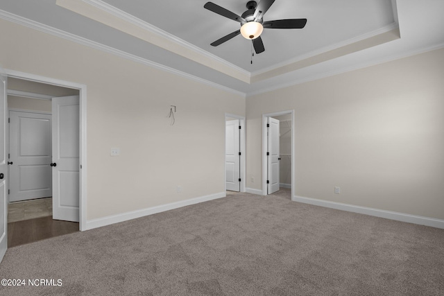 carpeted empty room with ceiling fan, a tray ceiling, and crown molding