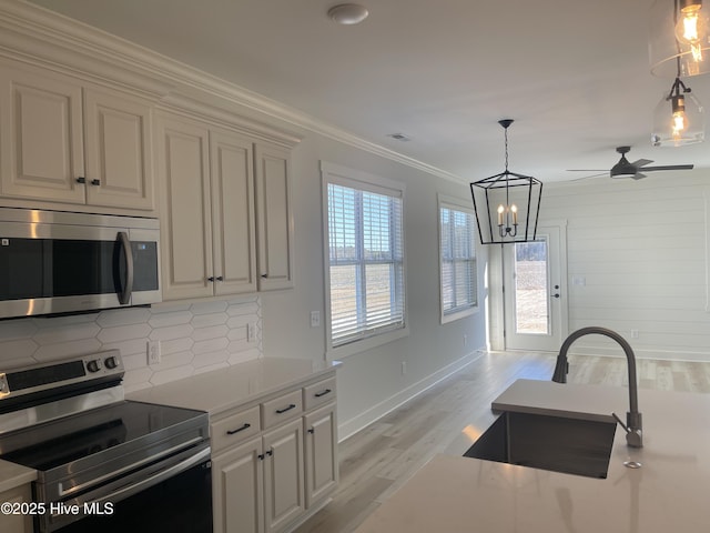 kitchen with sink, crown molding, stainless steel appliances, tasteful backsplash, and light wood-type flooring