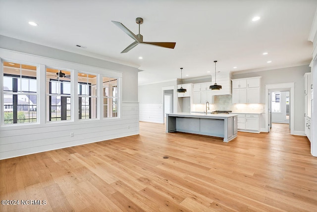 unfurnished living room featuring ceiling fan, crown molding, light hardwood / wood-style flooring, and sink