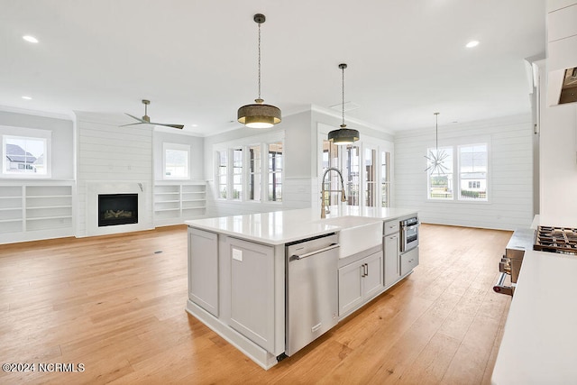 kitchen featuring decorative light fixtures, a center island with sink, light hardwood / wood-style floors, and stainless steel appliances