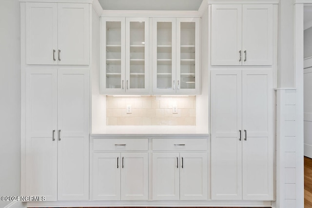 bar featuring hardwood / wood-style floors, white cabinetry, and backsplash