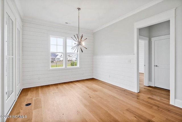 empty room featuring crown molding, a notable chandelier, and light hardwood / wood-style flooring