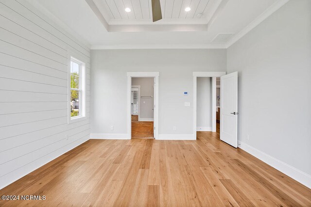 unfurnished bedroom featuring light wood-type flooring and a raised ceiling