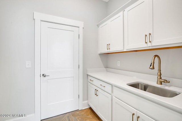 kitchen with light parquet floors, sink, and white cabinets