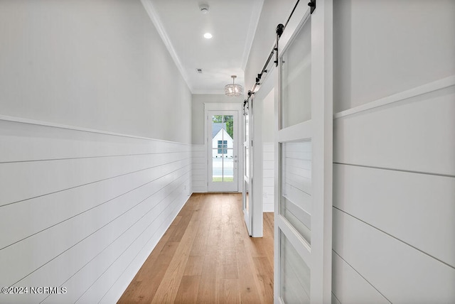 hall with crown molding, light hardwood / wood-style floors, and a barn door