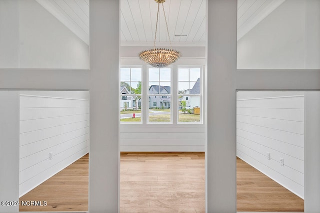 additional living space with a notable chandelier and light wood-type flooring