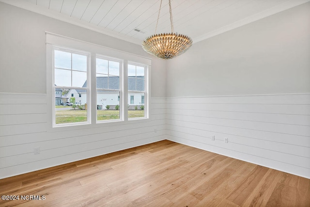 spare room featuring a chandelier and light wood-type flooring