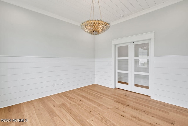 unfurnished room featuring light hardwood / wood-style flooring, crown molding, and an inviting chandelier