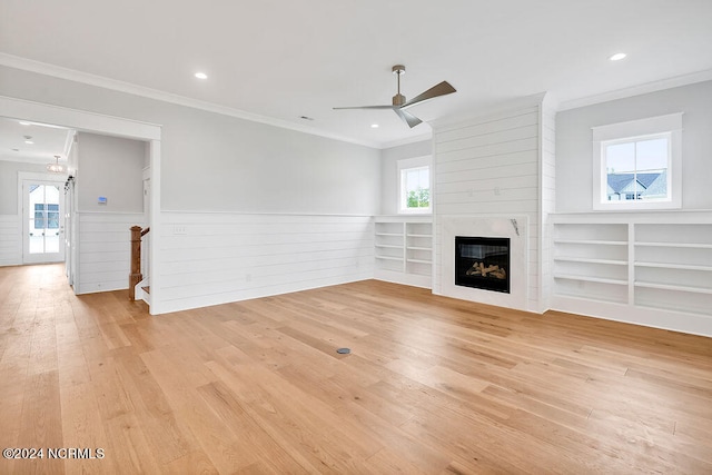 unfurnished living room featuring ornamental molding, light hardwood / wood-style floors, ceiling fan, and a fireplace