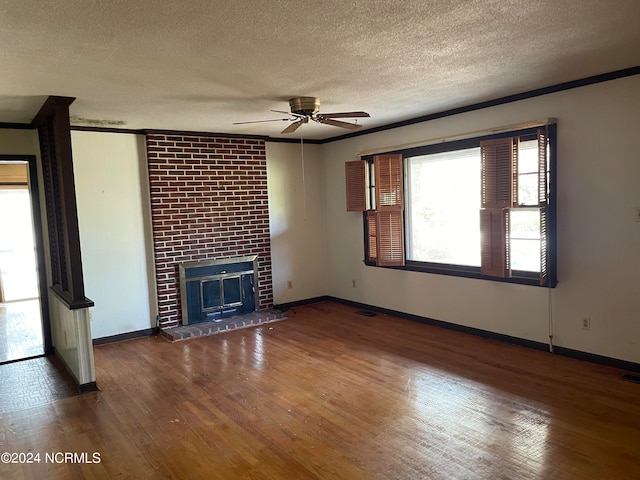 unfurnished living room with a fireplace, crown molding, a textured ceiling, dark hardwood / wood-style flooring, and ceiling fan