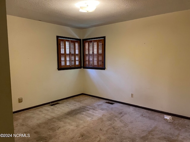 carpeted spare room featuring a textured ceiling