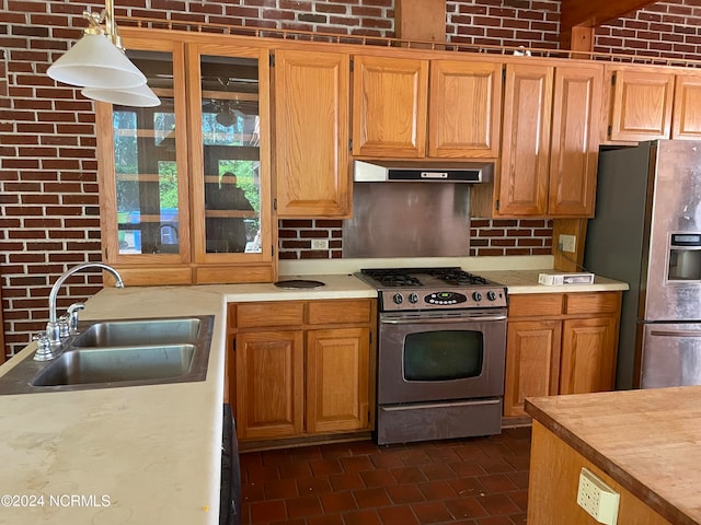 kitchen with pendant lighting, stainless steel appliances, sink, and brick wall