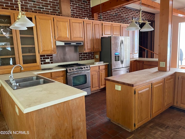 kitchen featuring decorative light fixtures, stainless steel appliances, sink, brick wall, and kitchen peninsula