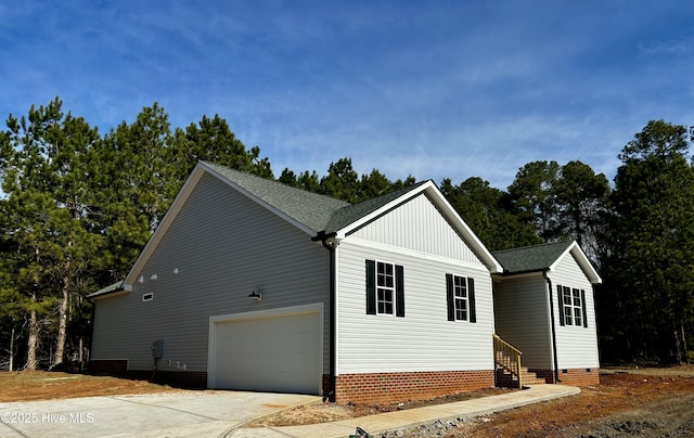 view of side of property featuring entry steps, an attached garage, driveway, crawl space, and roof with shingles