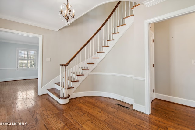 stairway with a chandelier, wood-type flooring, and crown molding