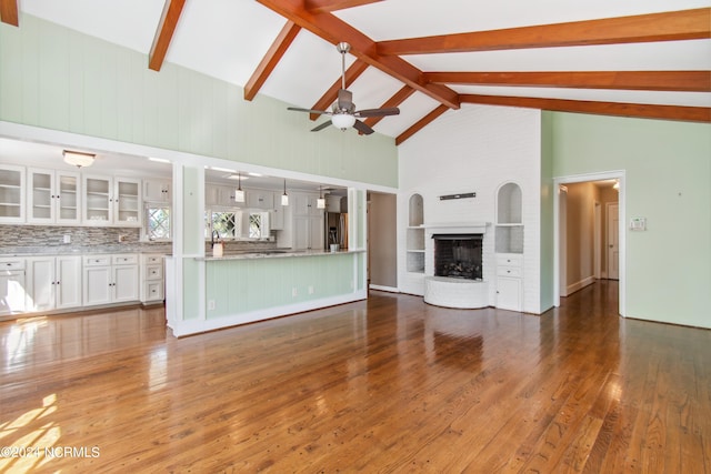 unfurnished living room featuring dark hardwood / wood-style flooring, high vaulted ceiling, a fireplace, and beamed ceiling