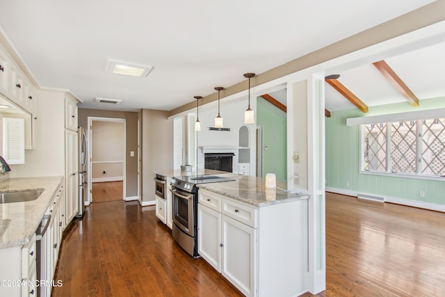 kitchen with dark hardwood / wood-style floors, a brick fireplace, stainless steel range with electric stovetop, and white cabinetry