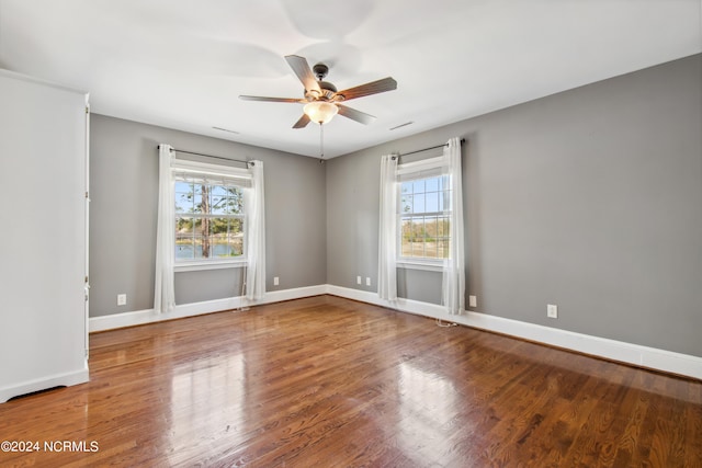 spare room featuring ceiling fan, dark hardwood / wood-style floors, and a healthy amount of sunlight