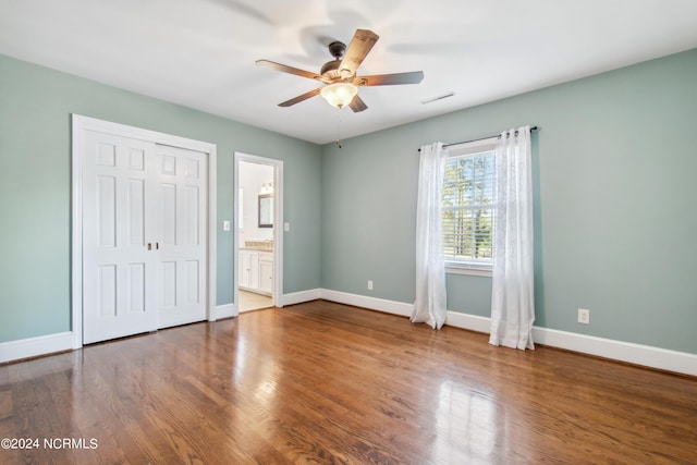 unfurnished bedroom featuring connected bathroom, a closet, ceiling fan, and dark hardwood / wood-style flooring