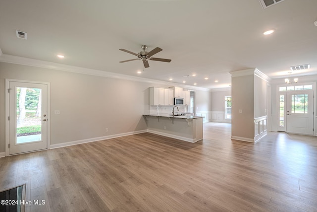 unfurnished living room with light hardwood / wood-style floors, ceiling fan, ornamental molding, and sink