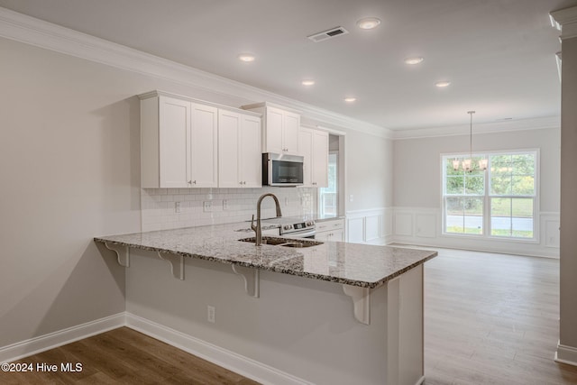 kitchen with kitchen peninsula, appliances with stainless steel finishes, light hardwood / wood-style flooring, and white cabinetry