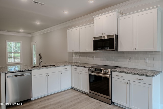 kitchen with stainless steel appliances, white cabinetry, light hardwood / wood-style floors, and sink