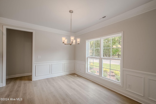 empty room featuring a chandelier, ornamental molding, and light hardwood / wood-style flooring