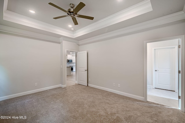 unfurnished bedroom with a tray ceiling, ceiling fan, and ornamental molding