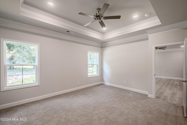 carpeted empty room featuring a tray ceiling, ceiling fan, and ornamental molding