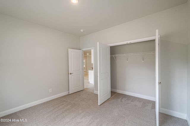 unfurnished bedroom featuring light colored carpet and a closet