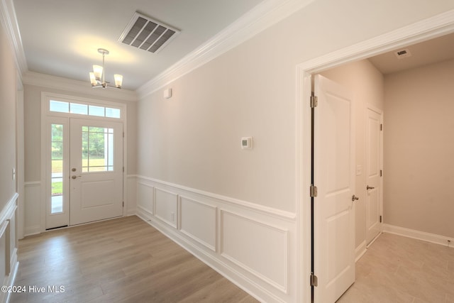 entryway featuring crown molding, light hardwood / wood-style flooring, and a chandelier