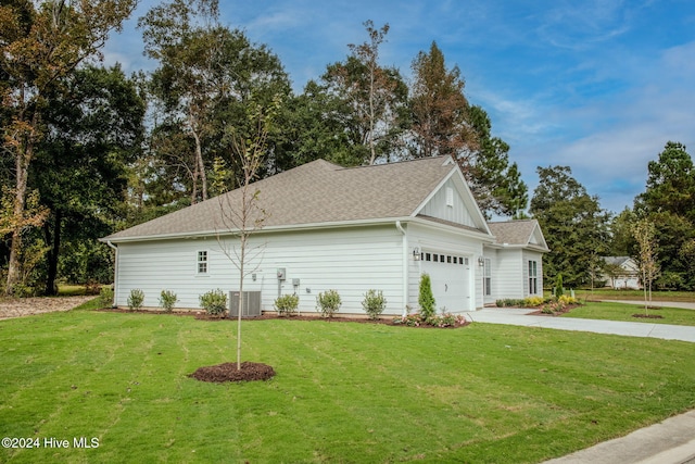 view of side of property featuring a lawn, a garage, and central AC