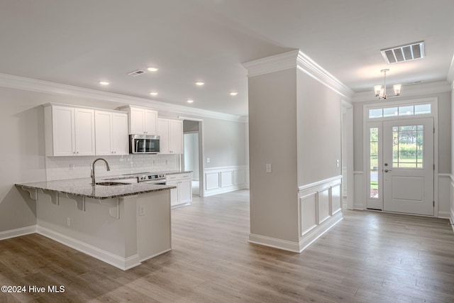 kitchen featuring kitchen peninsula, white cabinetry, sink, and light wood-type flooring