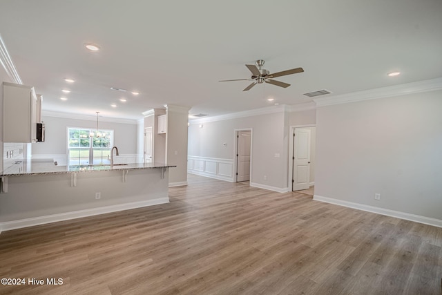 unfurnished living room with ceiling fan with notable chandelier, light hardwood / wood-style floors, sink, and crown molding