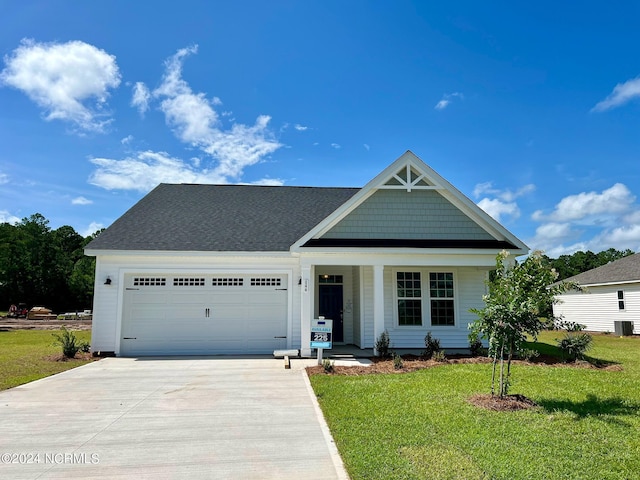 view of front of home with a porch, a garage, central air condition unit, and a front yard