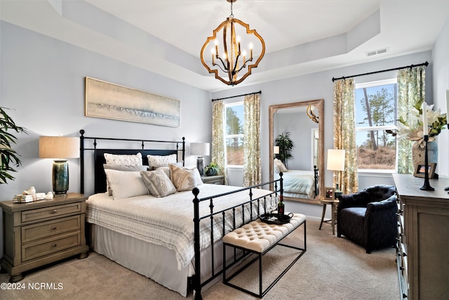 carpeted bedroom with a tray ceiling and an inviting chandelier