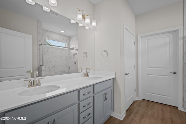 bathroom with hardwood / wood-style flooring, vanity, and a shower with door