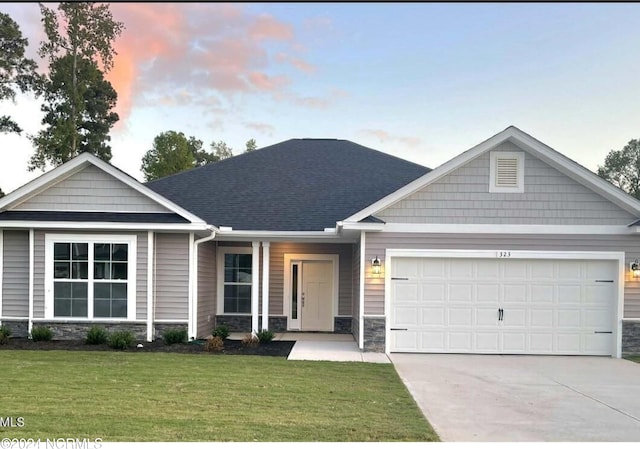 craftsman-style home featuring a shingled roof, concrete driveway, a lawn, a garage, and stone siding