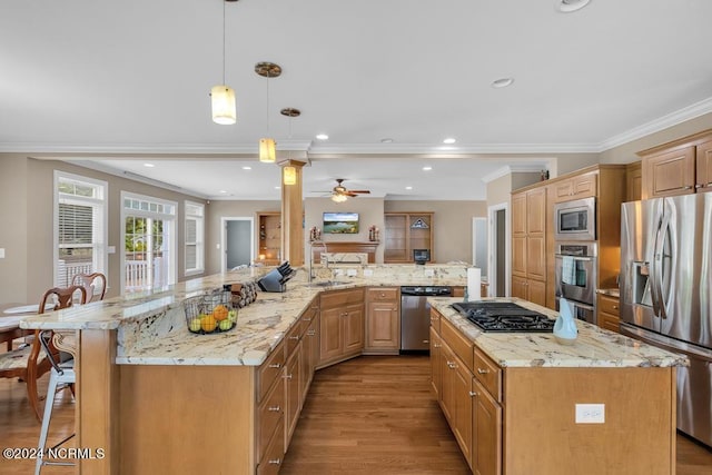 kitchen featuring a large island, stainless steel appliances, pendant lighting, a breakfast bar, and ornamental molding